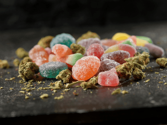 An assortment of colorful Delta-9 THC gummies scattered on a dark surface, surrounded by hemp flowers, showcasing a variety of flavors and textures.