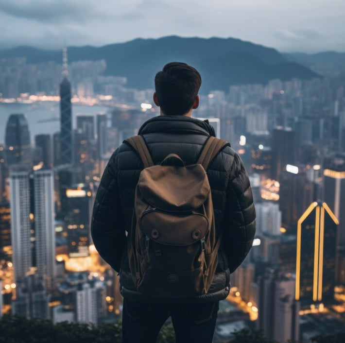 Backpacker standing on rooftop overlooking a city skyline at sunrise, symbolizing ambition, adventure, and new beginnings.